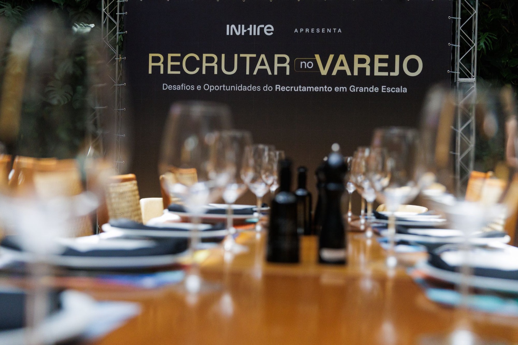 Mesa posta com o painel do Recrutar no Varejo ao fundo